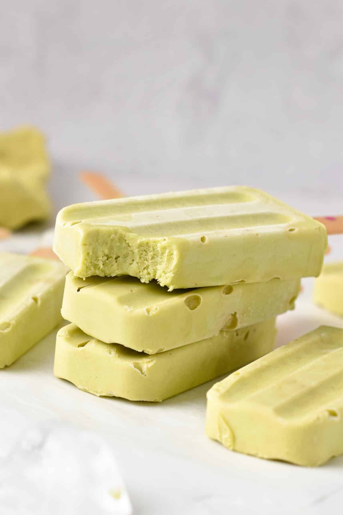 A stack of Avocado Popsicles with a wooden stick.