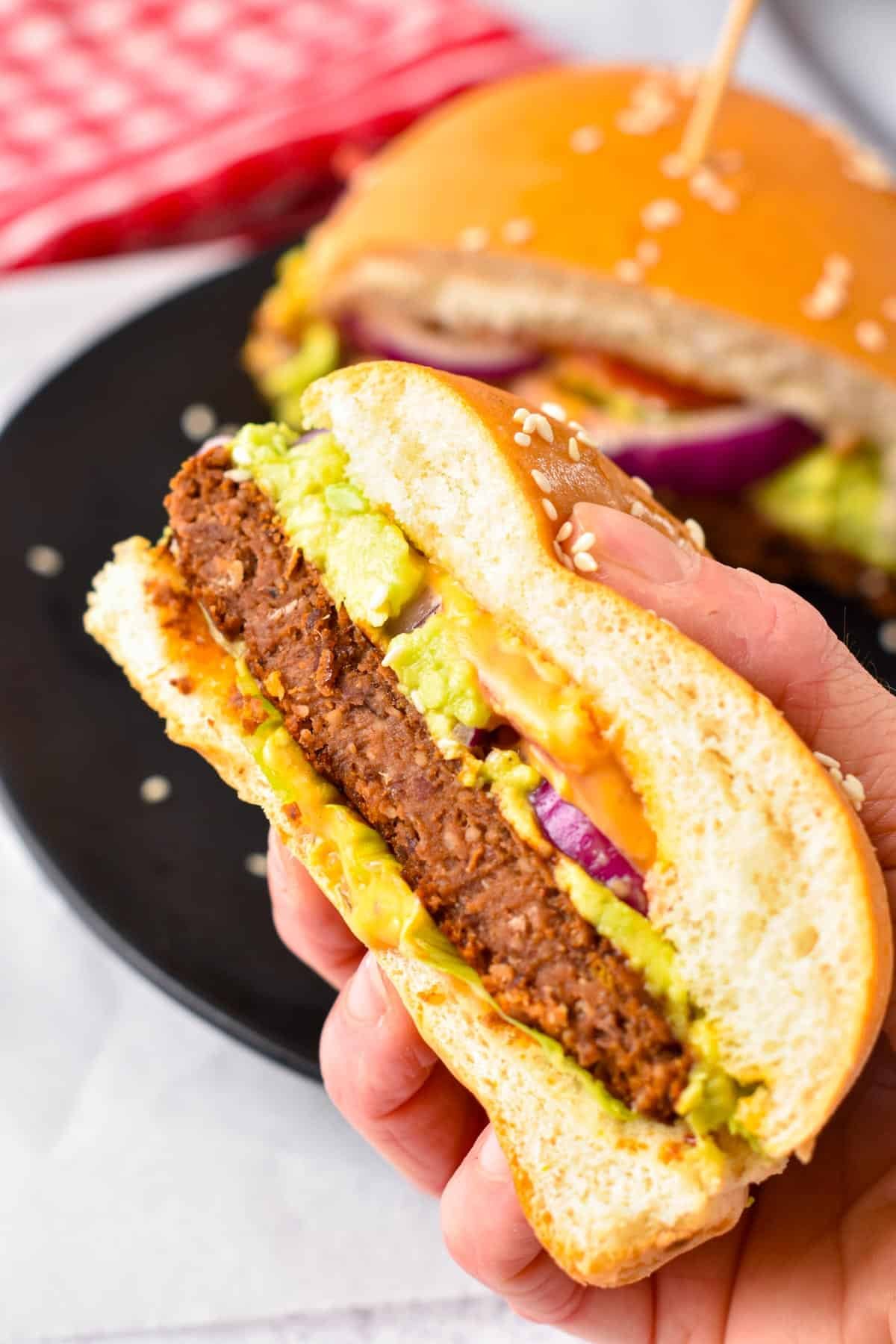 A hand holding half of a sweet potato black bean burger