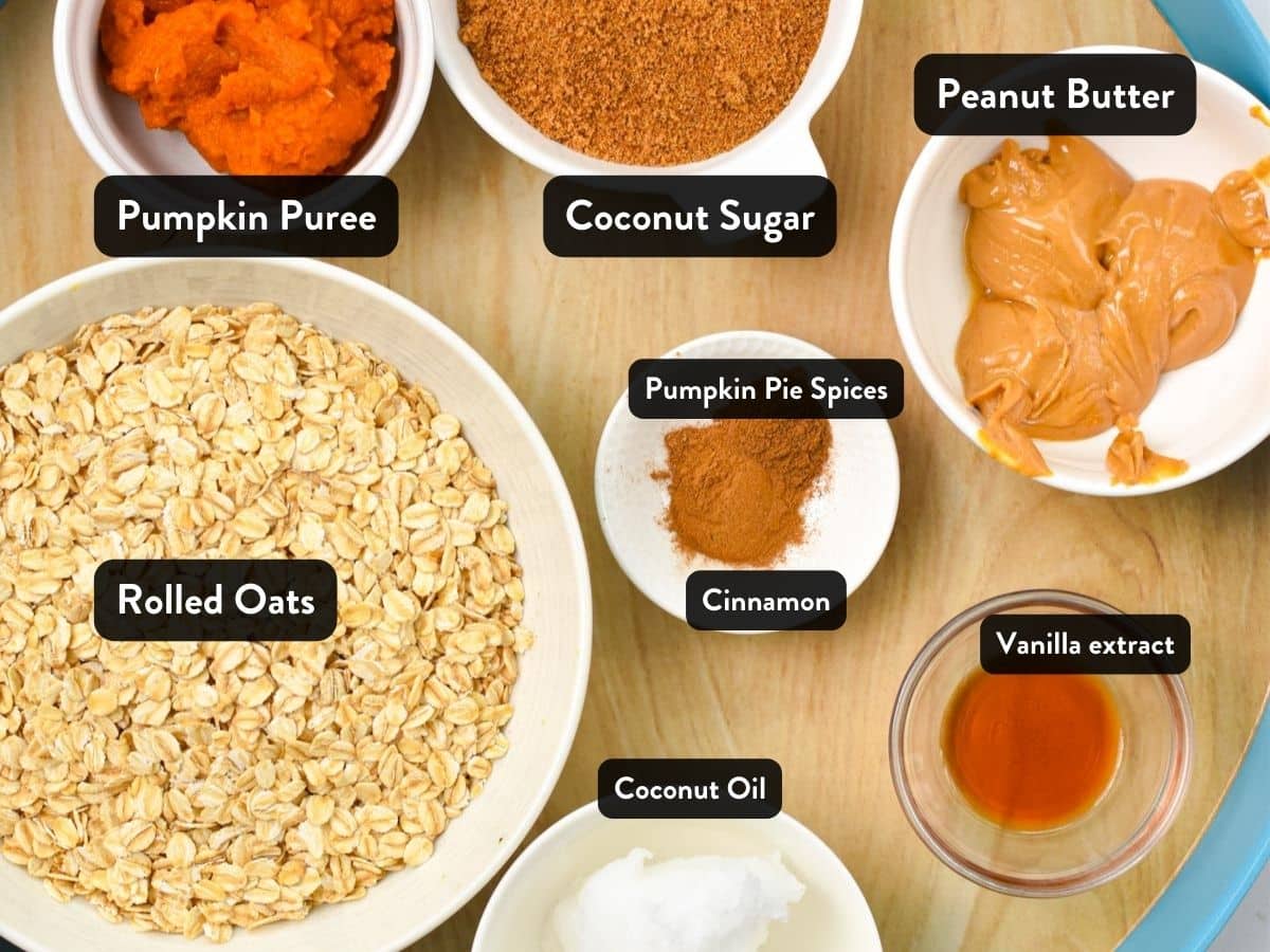 Ingredients with labels for the no-bake pumpkin cookies in small bowls and containers on a wooden tray.