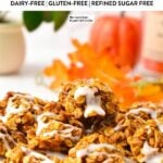 a plate filled with a stack of no-bake pumpkin cookies topped with a drizzle of icing sugar