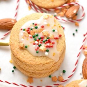 a stack of almond flour sugar cookies with royal icing and red, green, and golden sprinkles on top