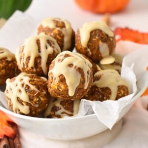 a bowl filled with no bake Pumpkin Energy Balls with a drizzle of white chocolate on top