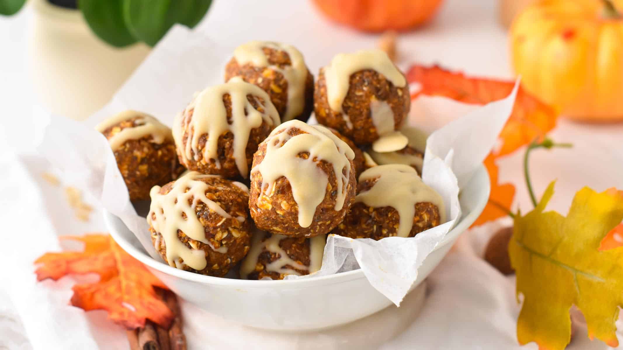 a bowl filled with no bake Pumpkin Energy Balls with a drizzle of white chocolate on top