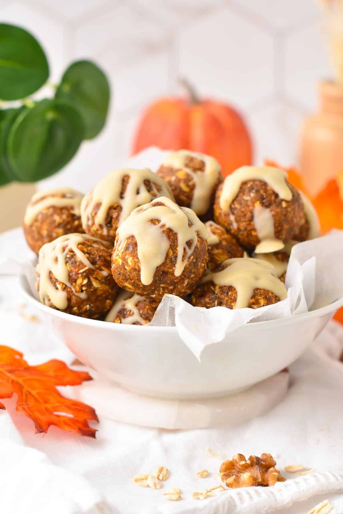 A bowl filled with no-bake Pumpkin Energy Balls with a drizzle of vegan white chocolate on the top.