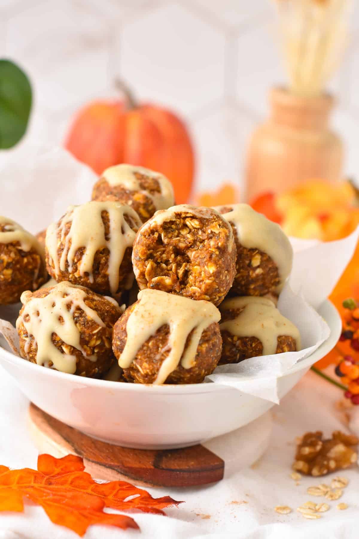 A bowl filled with no bake Pumpkin Energy Balls decorated with a drizzle of white chocolate on top.