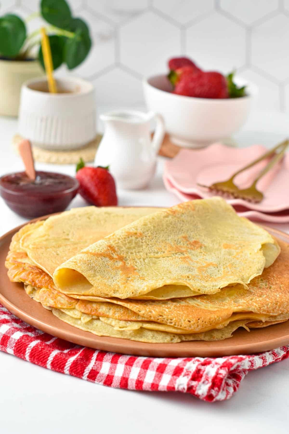 Vegan crepes on a large plate with plant-based toppings in the background.