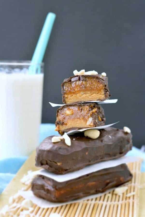 Raw Snickers Bars stacked with the top one cut in half.