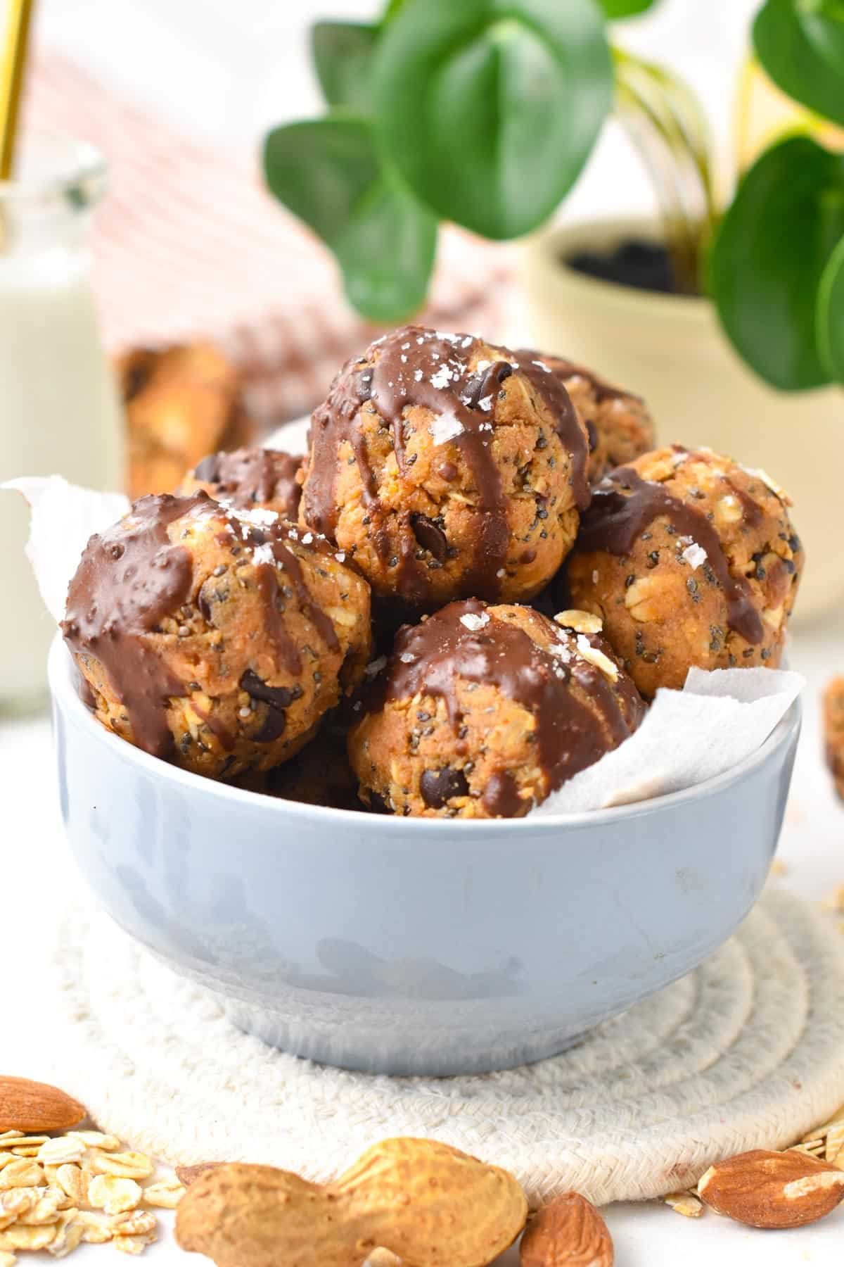 A stack of no-bake peanut butter protein balls filled with chia seeds, oats and flaxseed meal in a large blue ball.