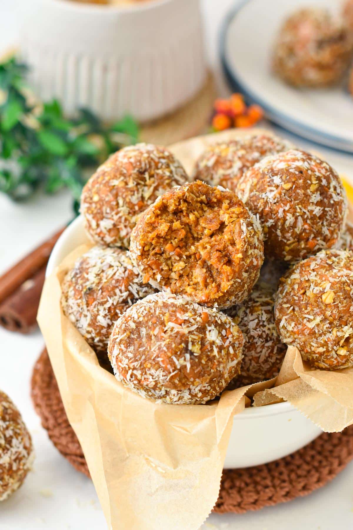 A bowl filled with a stack of no-bake carrot cake energy bites made with dates, nuts, and carrots.