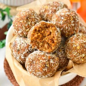 a ball filled with a stack of no-bake carrot cake energy bites made with dates, nuts, and carrots