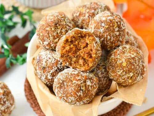a ball filled with a stack of no-bake carrot cake energy bites made with dates, nuts, and carrots
