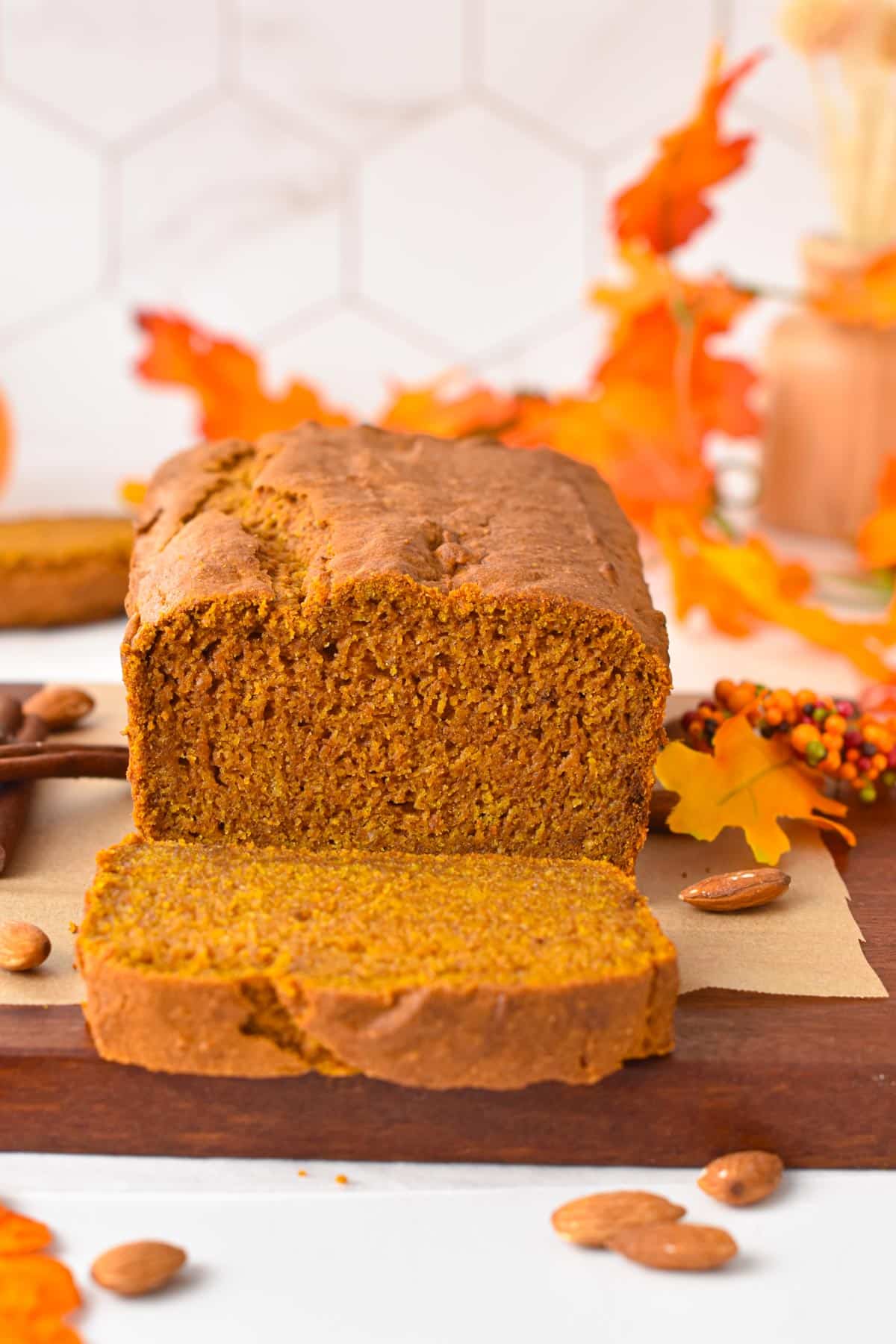 A sliced vegan gluten-free pumpkin bread with fall decoration in the background