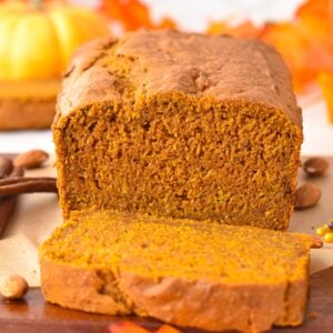 a picture showing a sliced vegan gluten-free pumpkin bread with fall decoration in the background