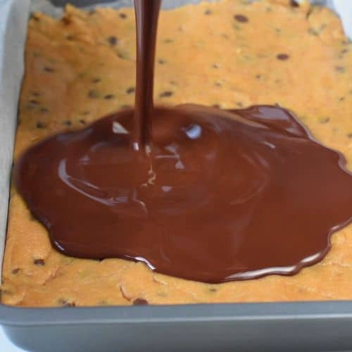 Pouring melted chocolate on the No-Bake Cookie Dough Bars base.