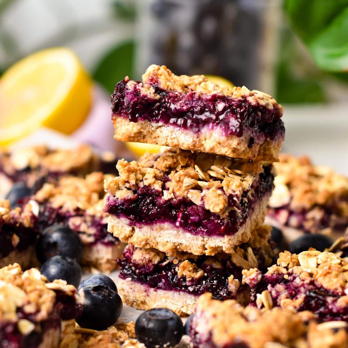 a stack of blueberry jam oatmeal bars with a lemon in the background