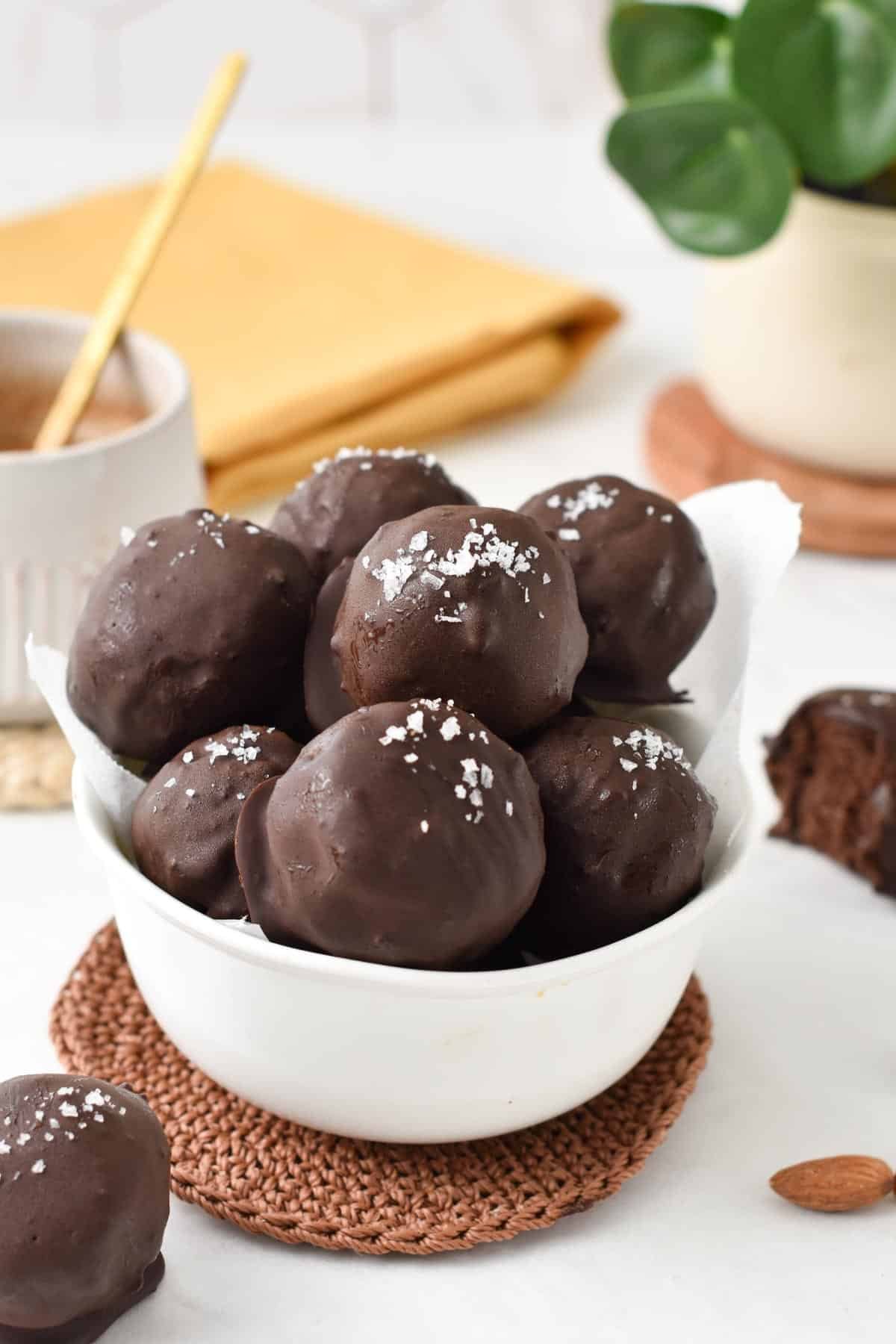 A bowl filled with no-bake brownie protein balls decorated with sea salt.