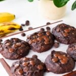 Six Chocolate Banana Cookies next to each other on a chopping board covered with white parchment paper