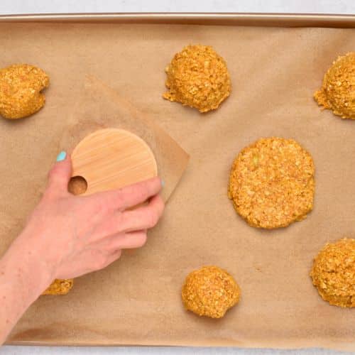 Flattening Pumpkin Banana Cookies on a cookie sheet.