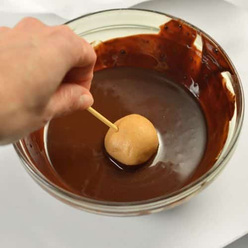 Dipping a vegan buckeye ball into melted chocolate.