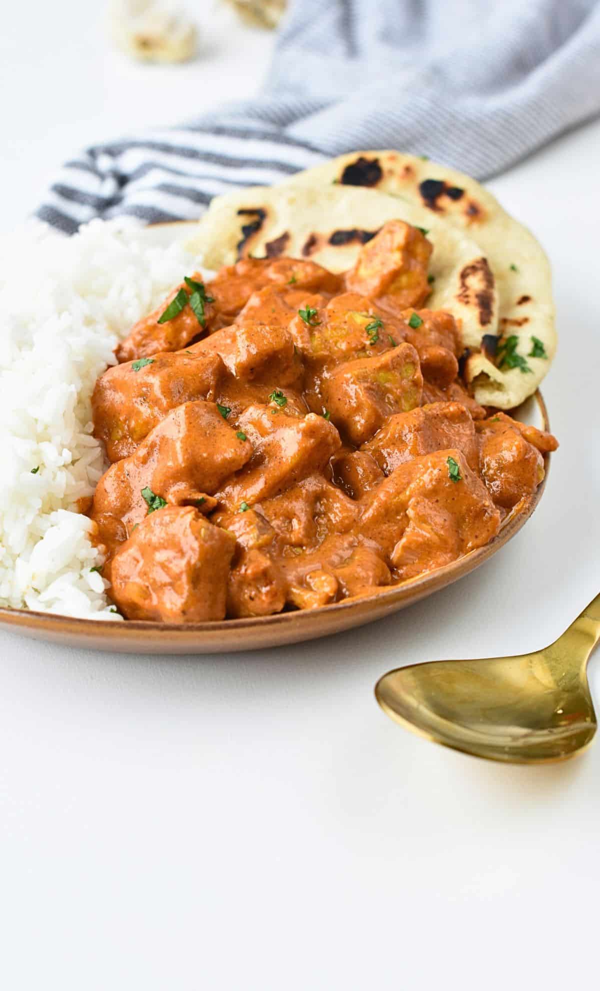 Vegan butter chicken on a plate with rice and vegan naans