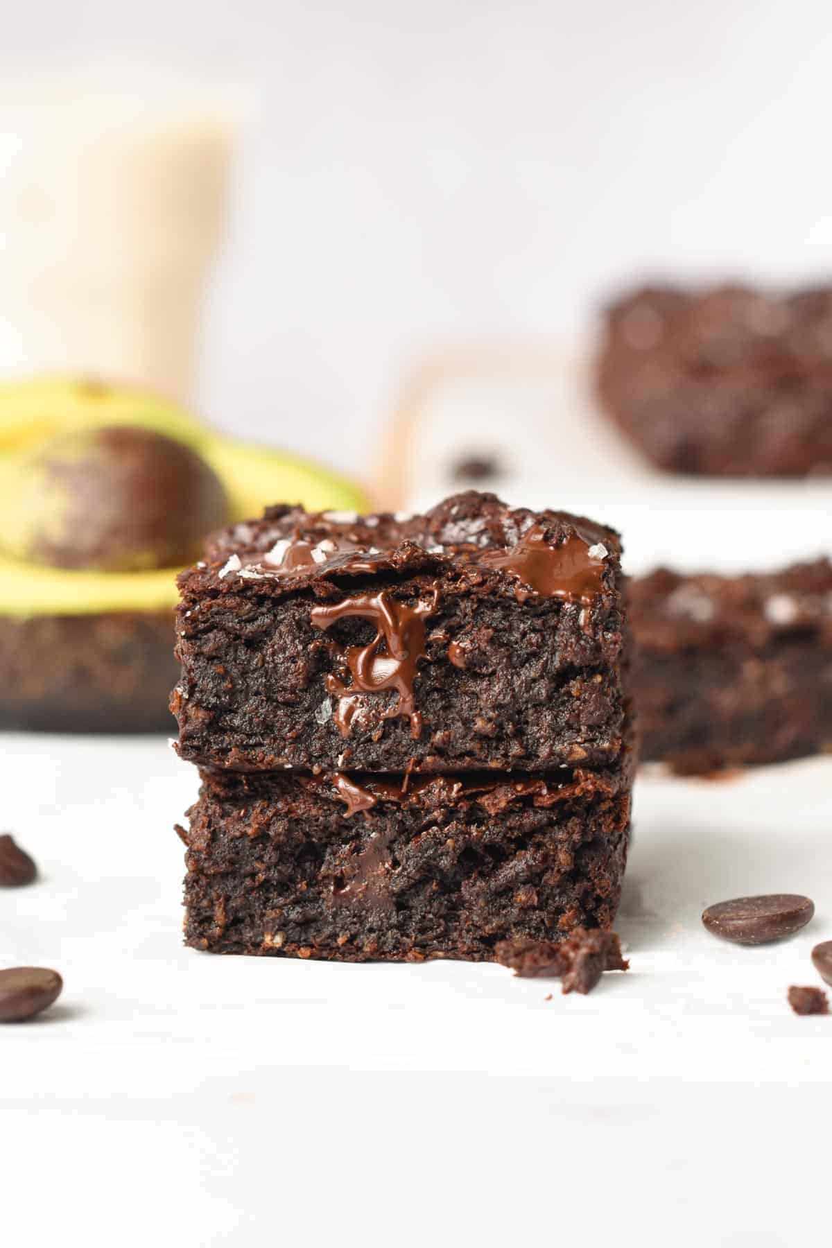 Avocado Brownies stacked in front of avocados.