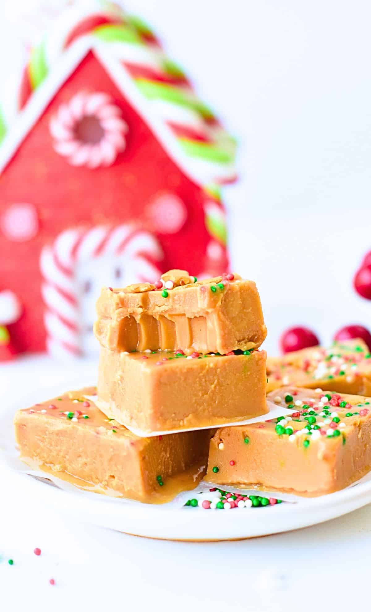 Healthy Peanut Butter Fudge stacked on a plate in front of Christmas decor.