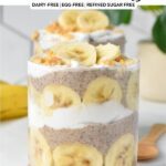 a glass jar filled with layers of banana slices, banana chia seed pudding, coconut yogurt and crumbled peanut butter cookie
