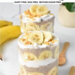 a glass jar filled with layers of banana slices, banana chia seed pudding, coconut yogurt and crumbled peanut butter cookie