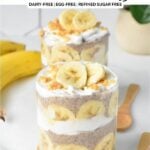 a glass jar filled with layers of banana slices, banana chia seed pudding, coconut yogurt and crumbled peanut butter cookie