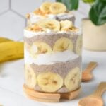 a glass jar filled with layers of banana slices, banana chia seed pudding, coconut yogurt and crumbled peanut butter cookie