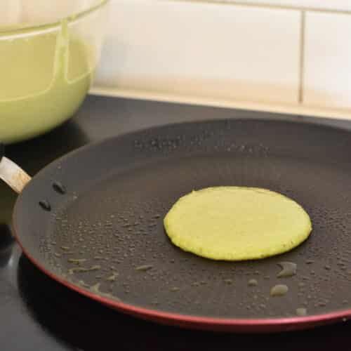 a green spinach pancake cooking on a grease pancake pan