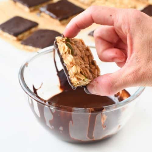 Dipping Healthy No-Bake Flapjacks in melted chocolate.