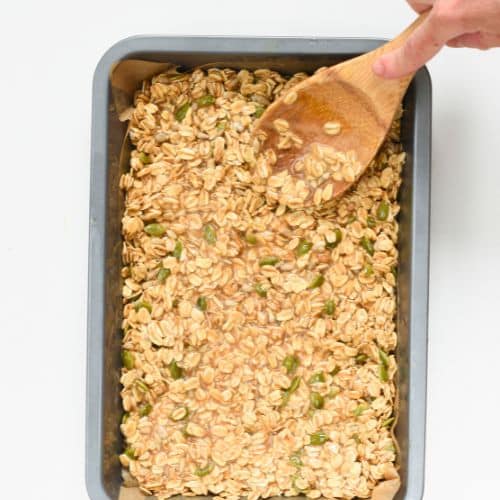 Spreading Healthy No-Bake Flapjacks on a baking sheet.