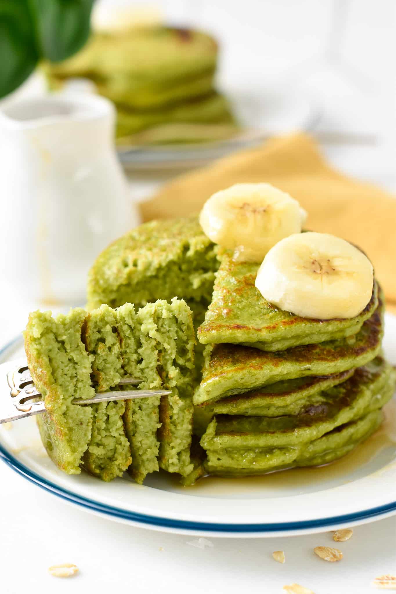 a stack of Spinach banana oat pancake with a fork holding a piece of the stack showing the vibrant green inside