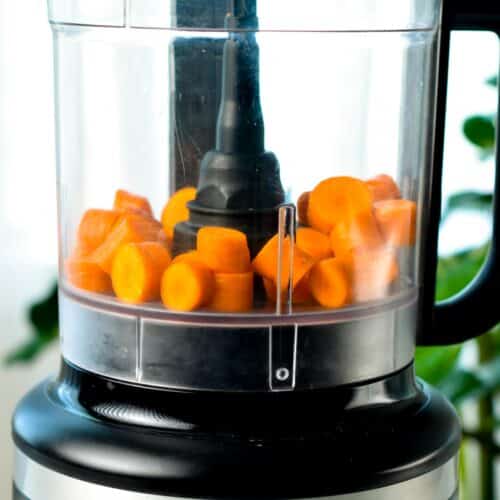 a food processor bowl with carrots chunk
