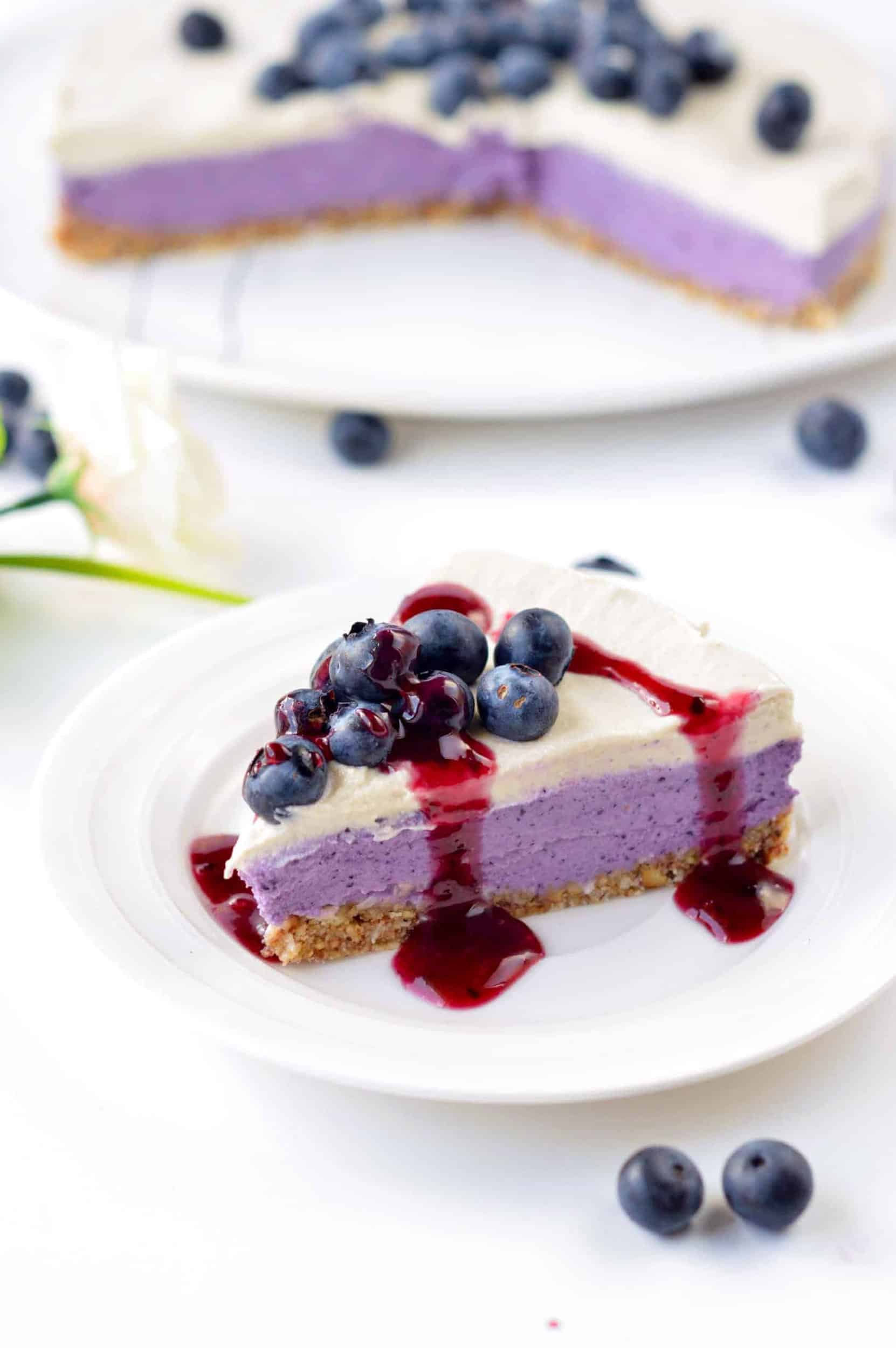 vegan blueberry cheesecake slice decorated with fresh blueberries and a blueberry coulis.