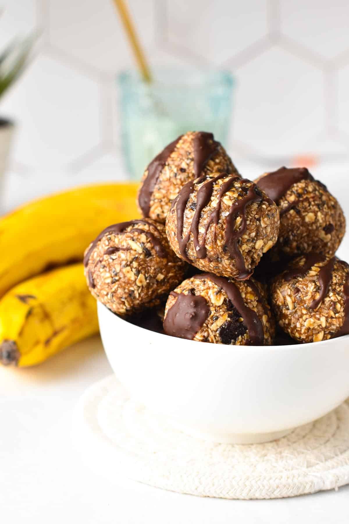 Banana Oat Balls in a white bowl, decorated with chocolate.