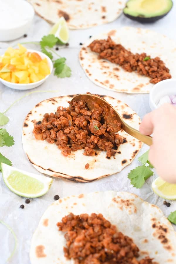Pouring Lentil taco meat on a small flatbread.