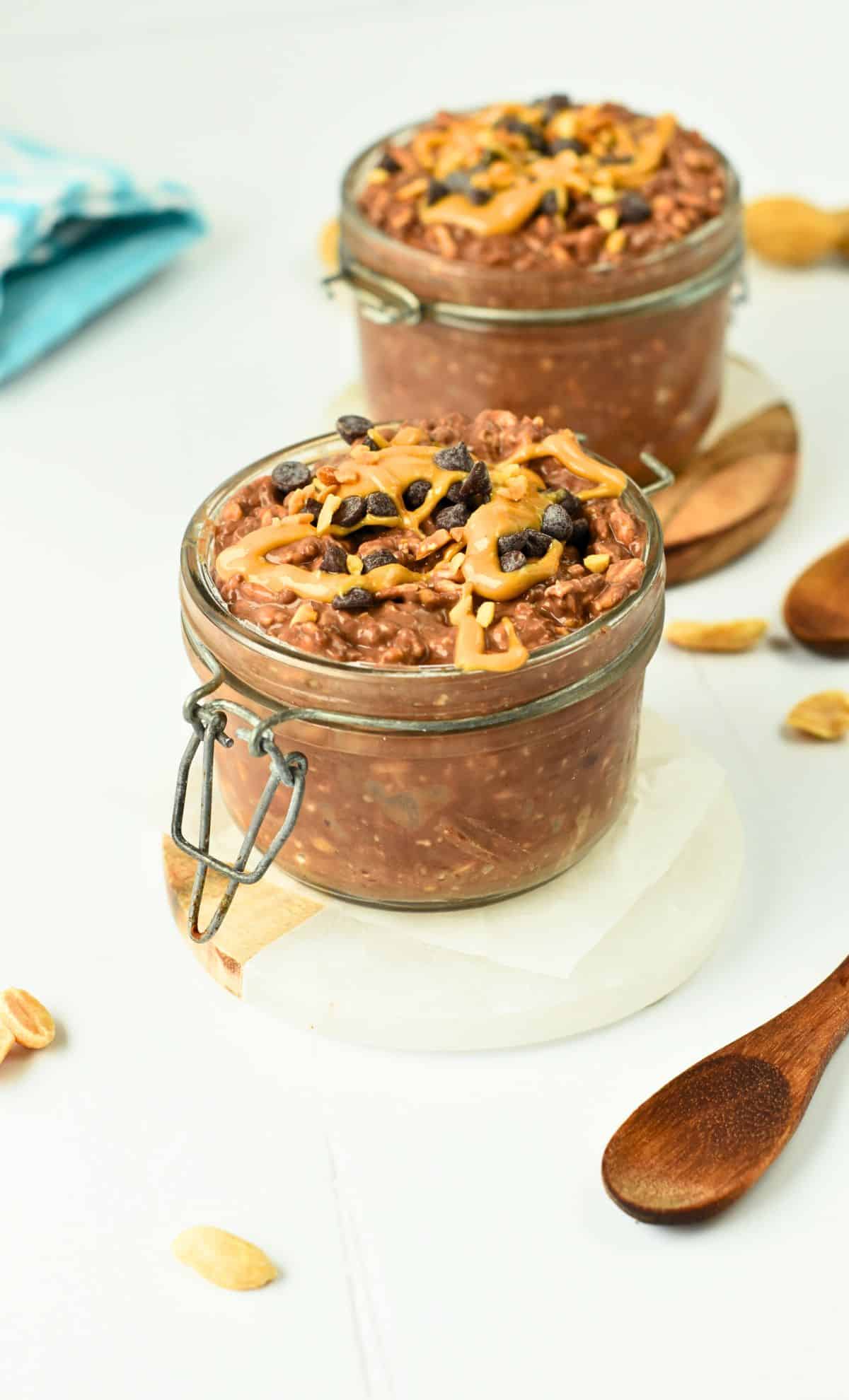 Chocolate Peanut Butter Overnight Oats in two jars decorated with fresh peanut butter.
