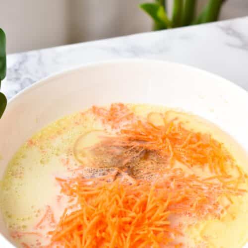 a bowl filled with mashed banana, shredded carrots, oil and almond milk