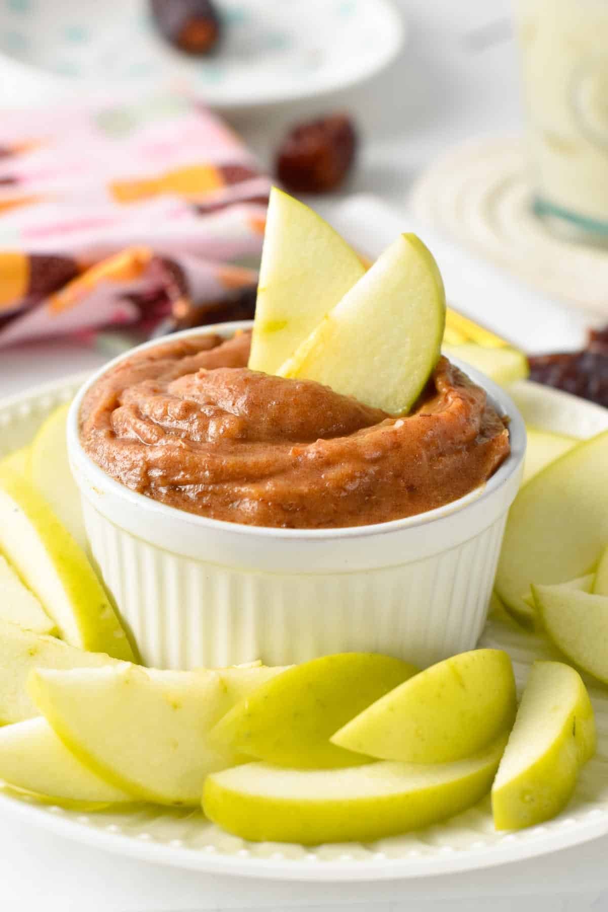 Date caramel sauce in a small ramekin decorated with apple slices.