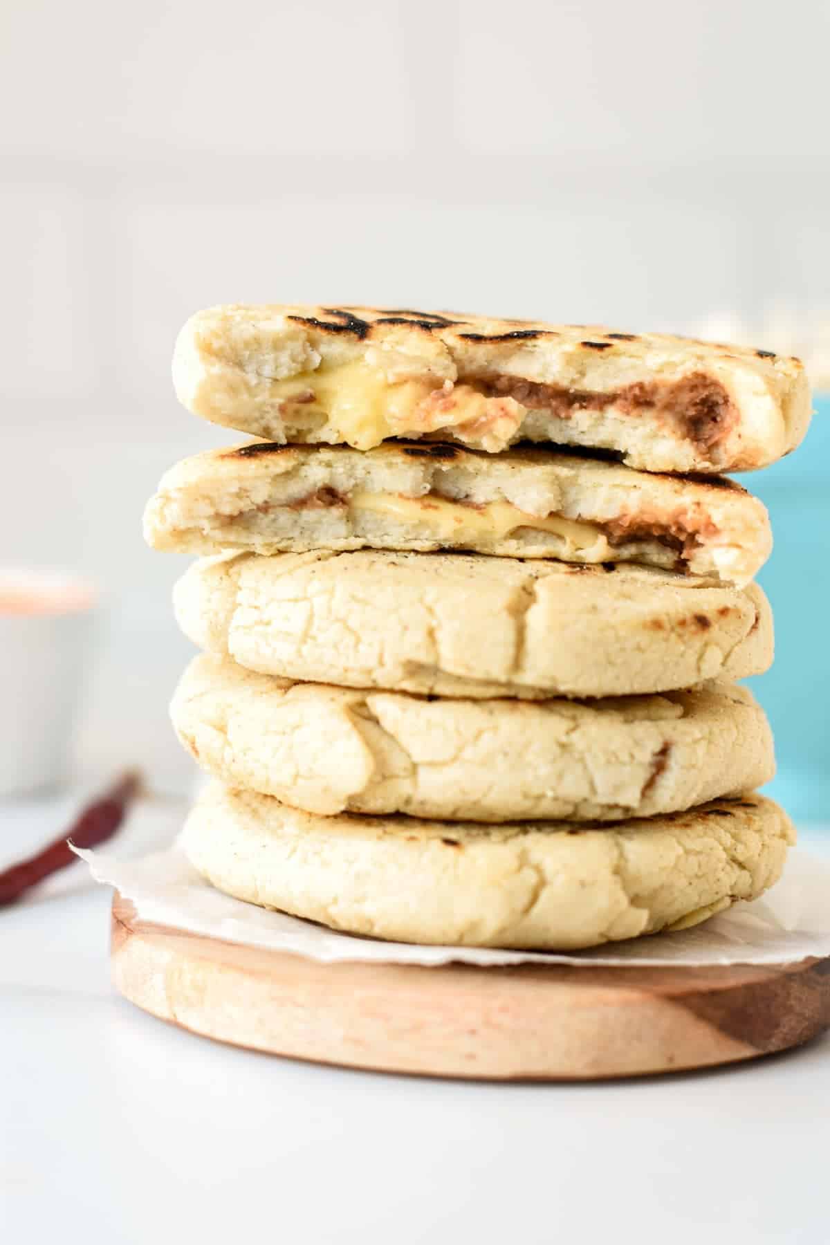 Vegan Pupusas stacked on a coaster with the top one sliced in half.