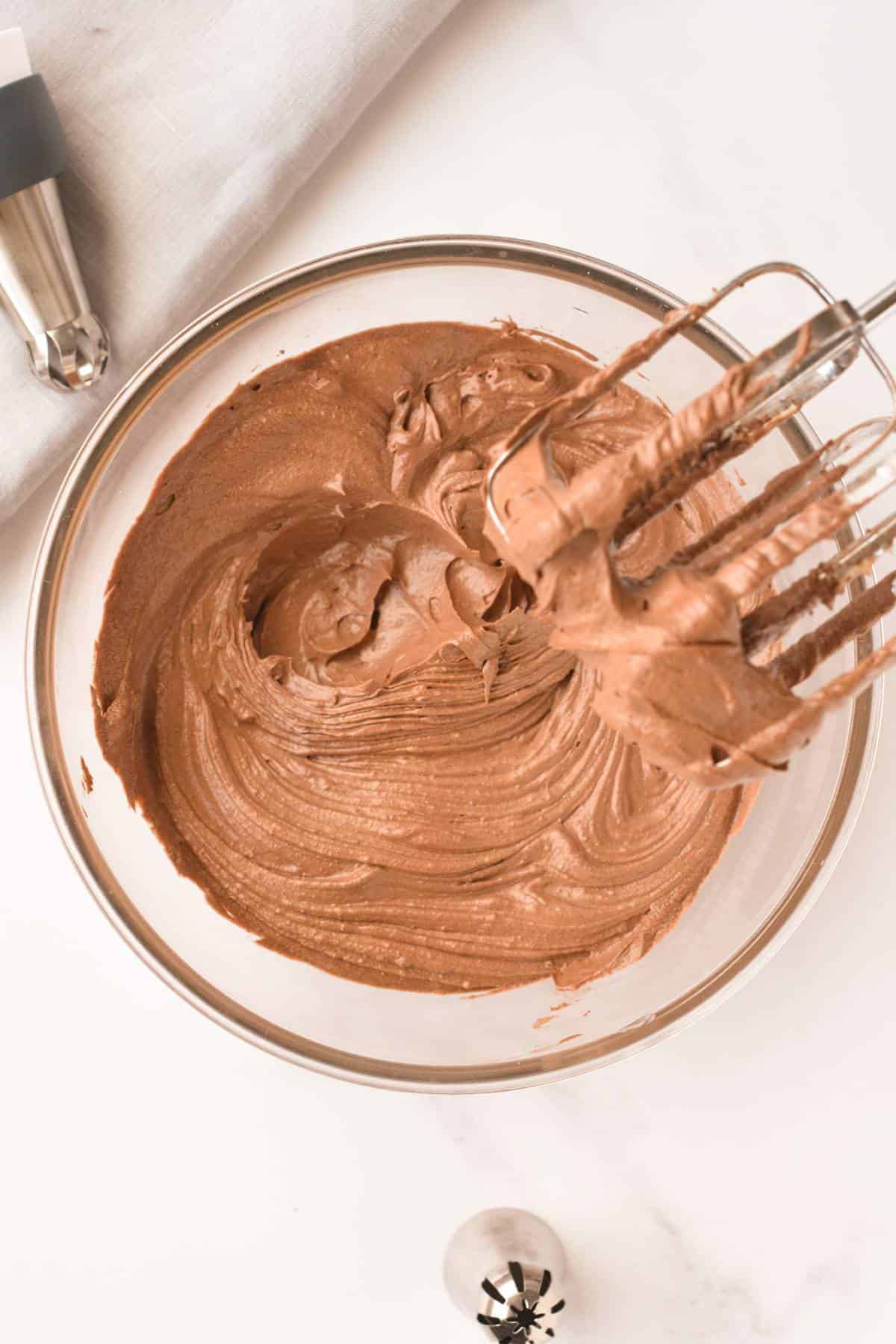 Vegan Chocolate Frosting in a mixing bowl  with a beater above.