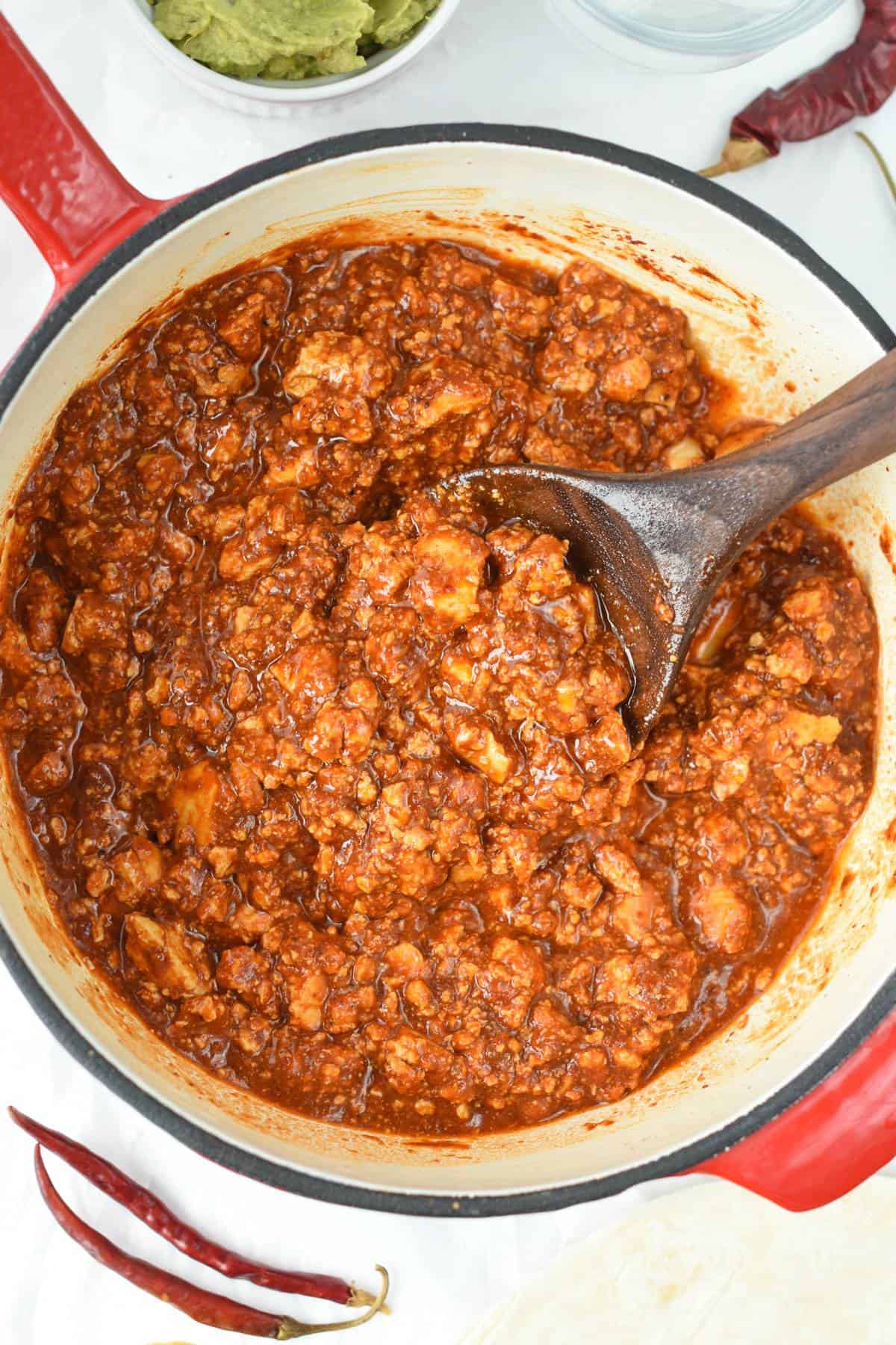 Sofritas cooking in a large cast-iron pan with a wooden spoon.