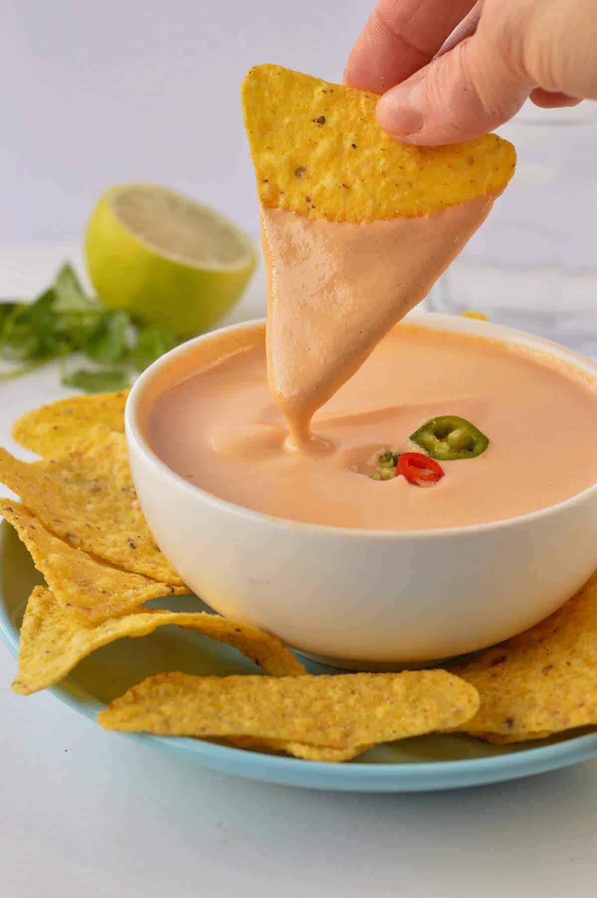 Dipping a corn tortilla in Vegan Nacho Cheese Sauce