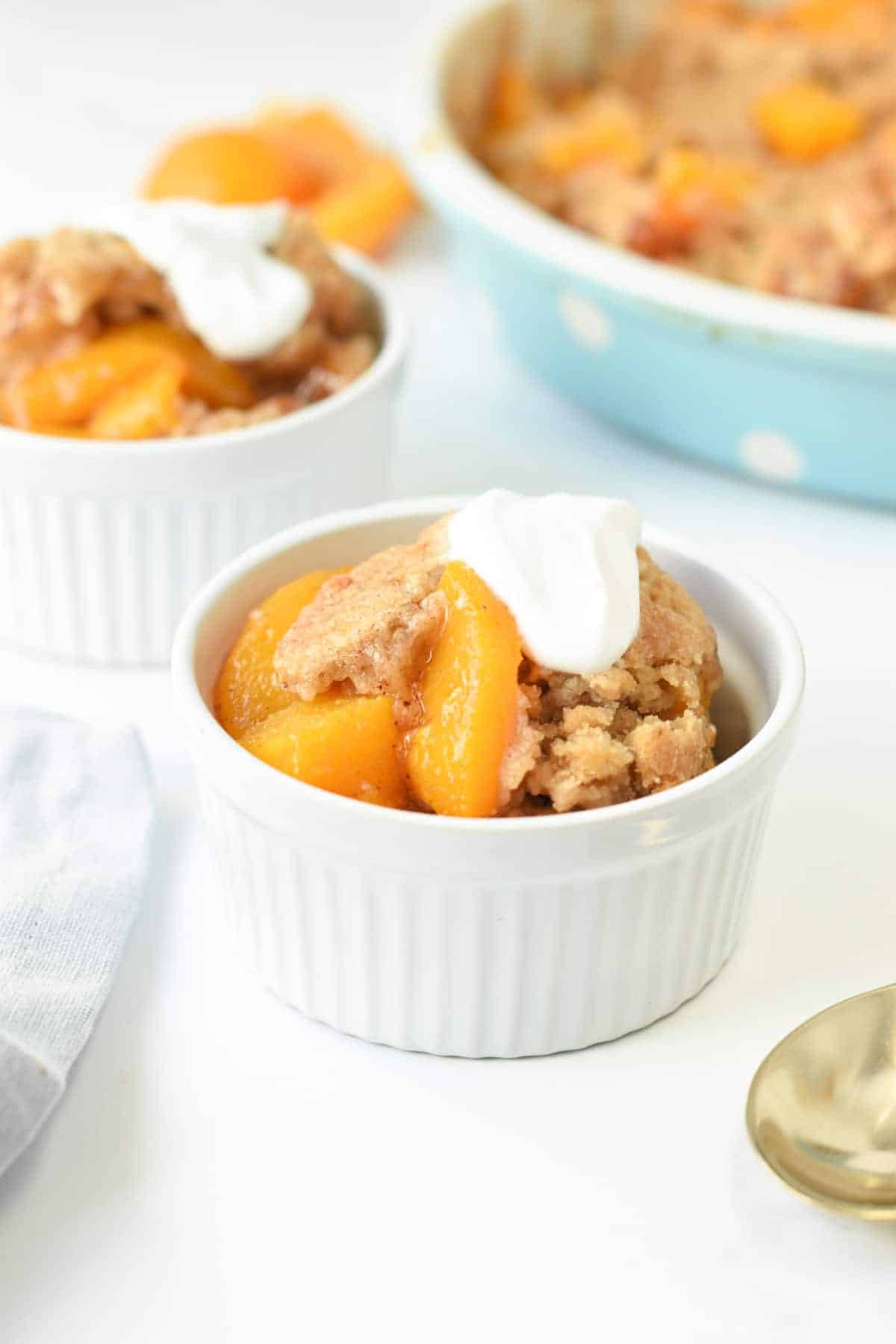 Vegan Peach Cobbler served in a small ramekin with a dollop of coconut yogurt.