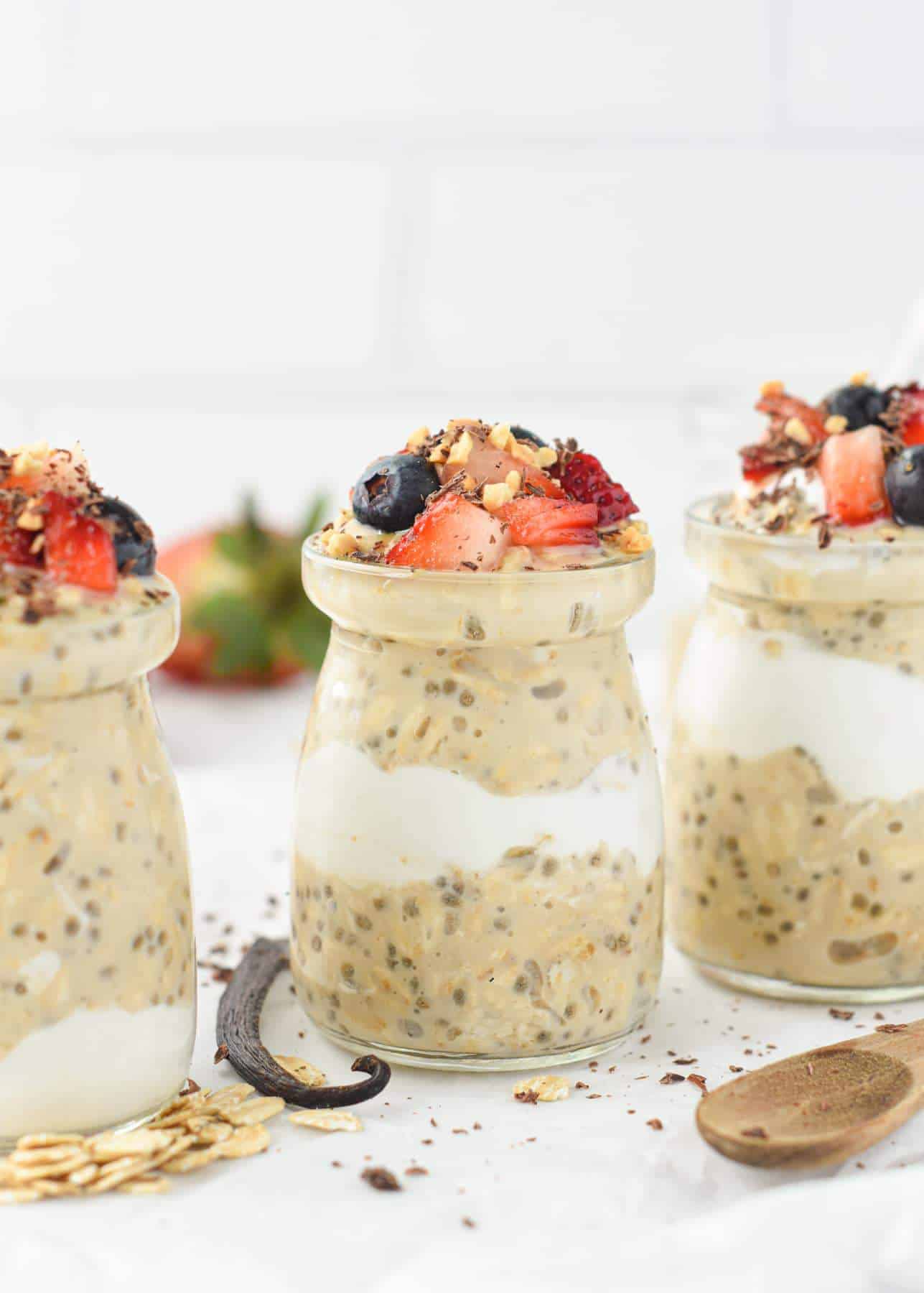 Three ramekins filled with Overnight Oats and a layer of coconut yogurt, topped with fresh fruits and nuts.