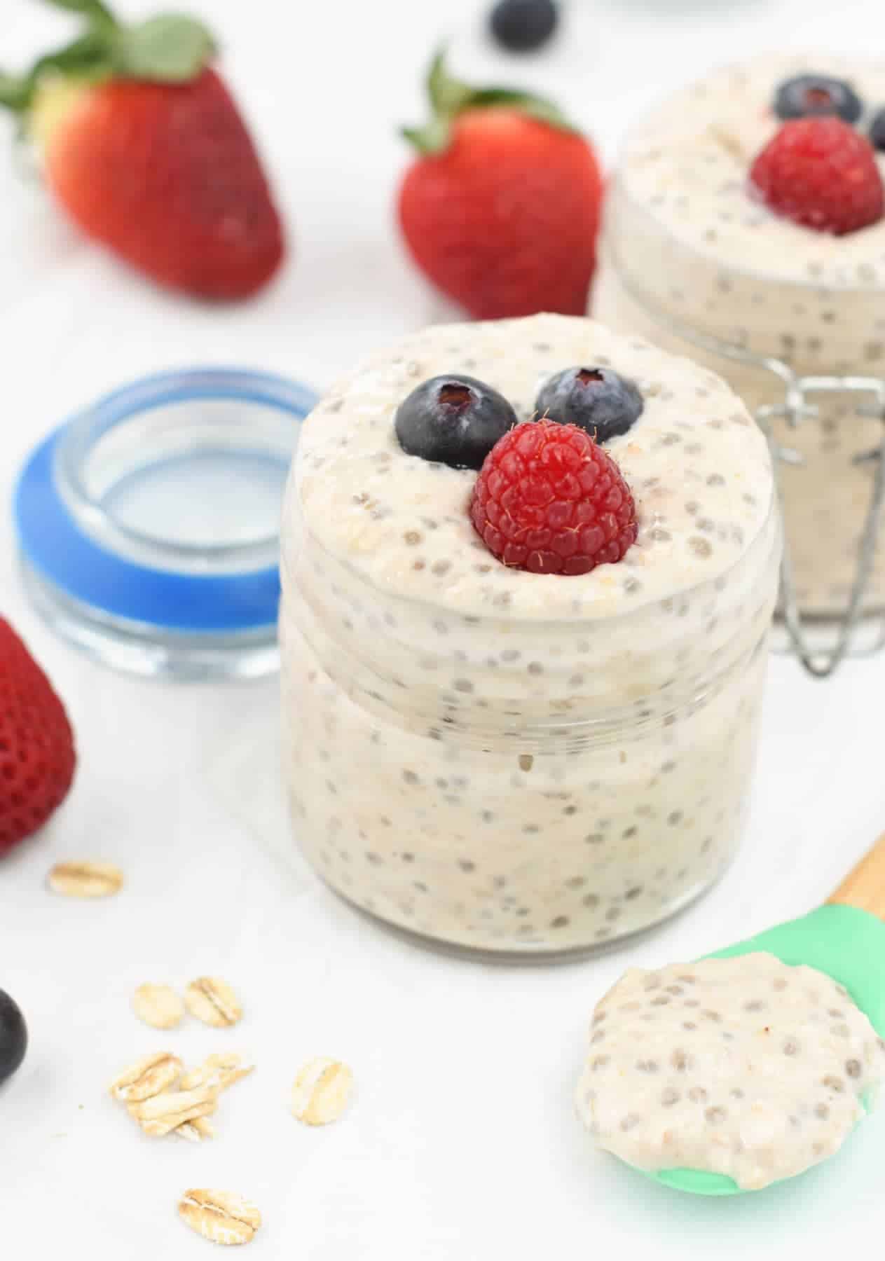 Overnight Oats for Toddler in a small serving jar, decorated with blueberries and a raspberry with another jar and strawberries in the background.
