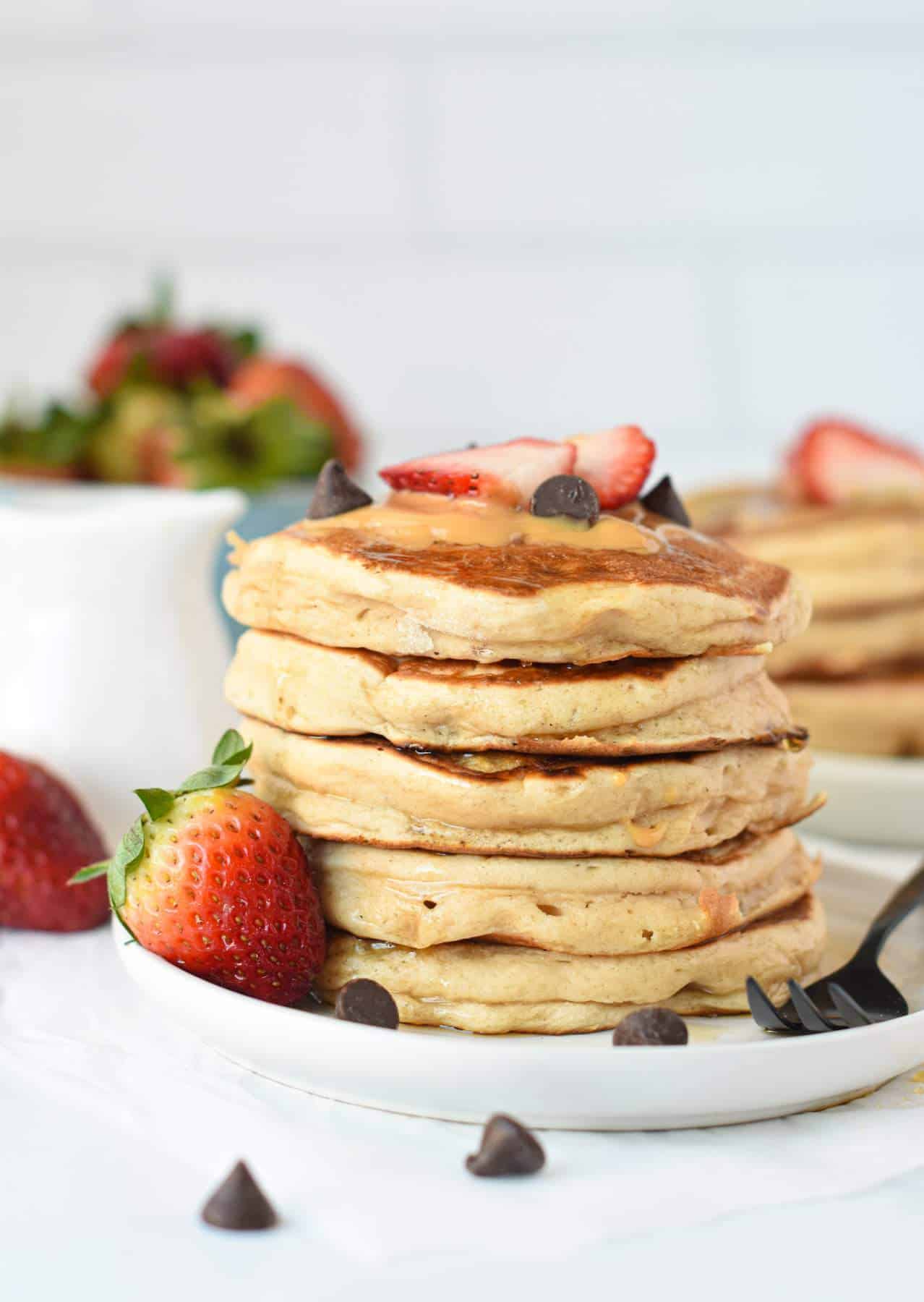 A stack of Vegan Protein Pancakes decorated with strawberries and blueberries.