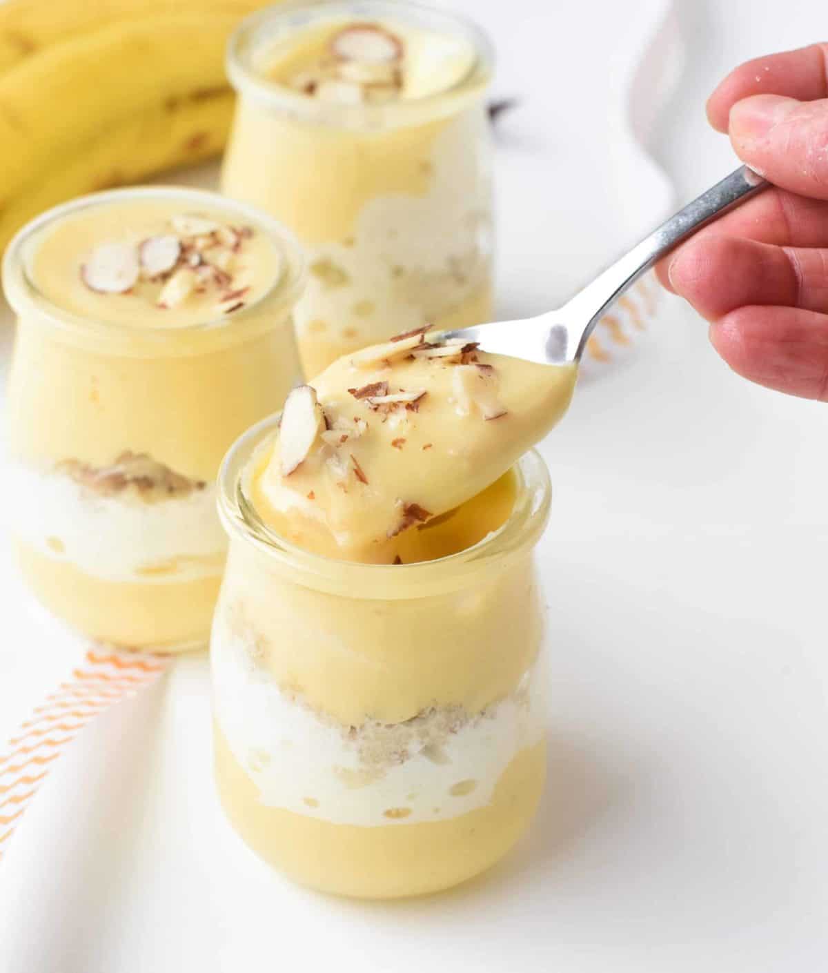 Vegan Banana Pudding in 3 jars with a spoon taking a serving.